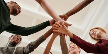 un groupe de collaborateurs qui tendent la main comme une équipe de sport