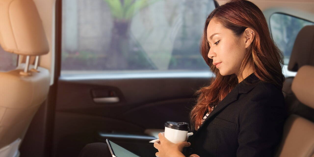 Une maanager prépare une réunion dans un taxi sur une tablette