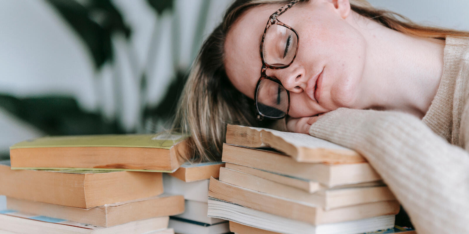 femme fatiguée, tête posée sur un tas de livre, symbole de la fatigue de l'apprentissage ou learning fatigue